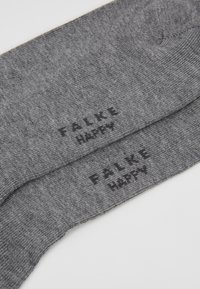 Grå strikkede sokker med sort tekst, der står "FALKE HAPPY" på siden, med en glat tekstur og et standard crew-længde design.