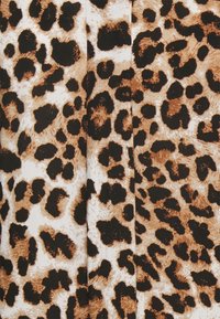 Tecido de padrão de leopardo com grandes manchas pretas irregulares sobre um fundo bege e branco, com uma superfície lisa e ligeiramente texturizada.