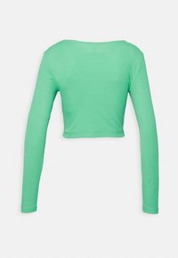 Top cropped a maniche lunghe verde a coste con scollo a barca, mostrato da dietro su uno sfondo bianco.