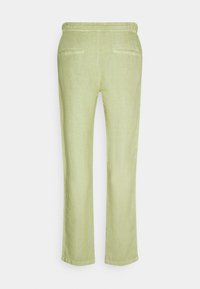 Pantalon droit vert clair avec une taille élastique et deux poches passepoilées à l'arrière, vu de dos sur fond blanc.