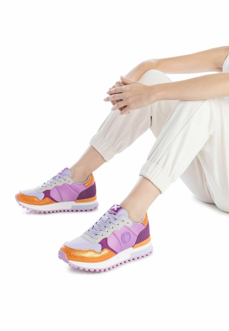 Sneakers sportivi caratterizzati da un mix di materiali viola, lavanda e arancione, con una tomaia in rete, suola in gomma e dettagli testurizzati.