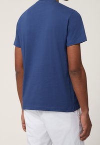 Marineblå bomulds-T-shirt med rund hals og korte ærmer. Glat tekstur med en afslappet pasform, vist bagfra.