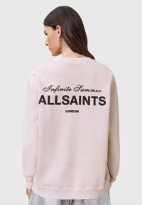 Svetloružová mikina s rebrovanými manžetami a lemom. Zadná strana obsahuje čierny text: "Infinite Summer ALLSAINTS LONDON" v tučnom a kurzívnom písmene.