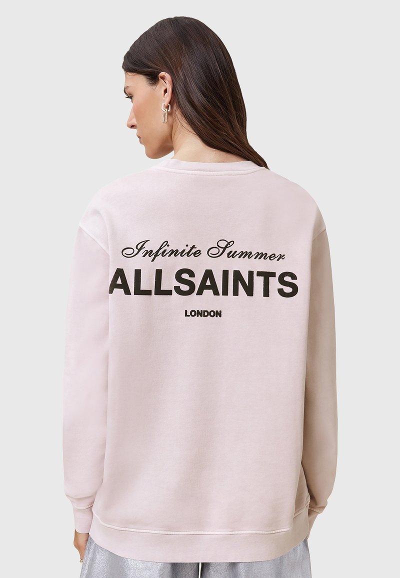 Svetloružová mikina s rebrovanými manžetami a lemom. Zadná strana obsahuje čierny text: "Infinite Summer ALLSAINTS LONDON" v tučnom a kurzívnom písmene.