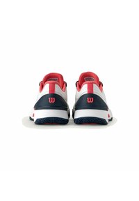 Zapatillas de tenis blancas y marinas con acentos rojos, parte superior de malla texturizada, cuello acolchado y logo distintivo en el talón.