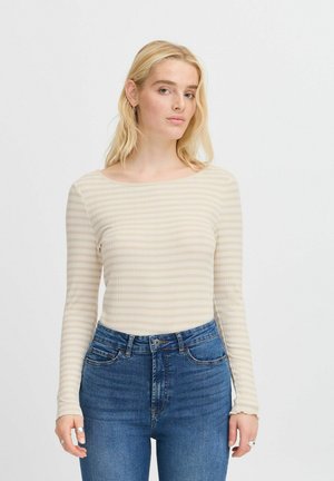 Langärmliges, geripptes Oberteil in Beige mit feinen Streifen. Verfügt über einen weiten Halsausschnitt und eine taillierte Silhouette. Kombiniert mit hochtaillierten blauen Jeans.