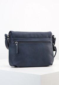 Marineblå læder crossbody taske med frontlomme med lynlås, justerbar skulderrem og struktureret overflade på hvidt display.