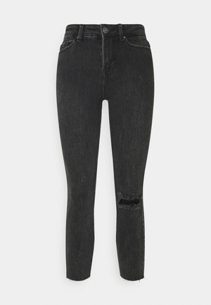 Jeans skinny negros de denim. Con una cintura de altura media y una rodilla desgastada con bordes deshilachados. Textura suave y diseño ajustado.