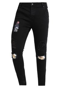 Black denim jeans with a slim fit, featuring distressed rips at the knees with floral fabric patches. Standard five-pocket design.