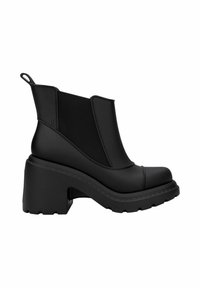 Bottines Chelsea noires avec un talon épais, en matériau lisse semblable au caoutchouc, dotées de panneaux latéraux en élasthanne et d'une languette à l'arrière pour un enfilage facile.