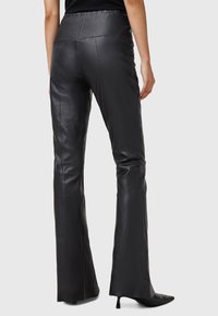 Black leather flared pants with a smooth texture, featuring a high waistband and mid-rise back. Cut with a slim fit through the thigh.