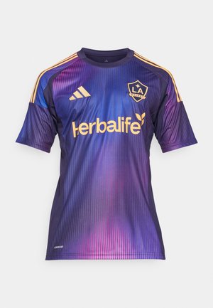 Maillot de football dégradé violet avec des rayures verticales, comportant des accents jaunes, le logo "Herbalife" et l'emblème "LA Galaxy" sur la poitrine.