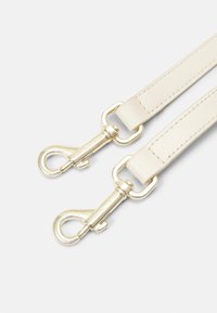 Cremfarbener Lederriemen mit Clips aus goldfarbigem Metall, ausgestattet mit glatter Textur, abgerundeten Kanten und Nahtdetails entlang der Länge.