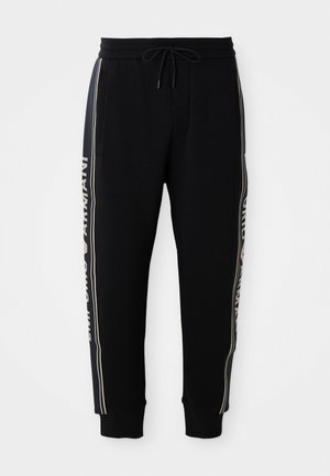 Sorte joggebukser med elastisk liv, snor, side lommer, ribbede mansjetter og hvit "Emporio Armani" tekst langs sidestroppene.