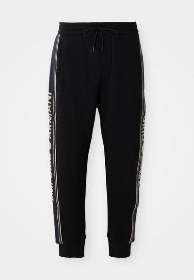 Mustad jogger püksid elastse vöökoha, paelaga, küljetaskutega, ribakantidega ja valge "Emporio Armani" tekstiga külgriietel.