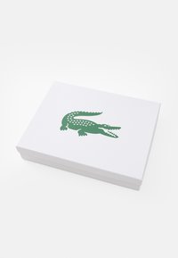 Biely obdĺžnikový box s potlačeným zeleným logom krokodíla na veku, umiestnený na bielej ploche.