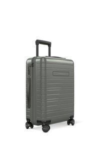 Valise rigide de couleur vert olive mat, présentant un design rainuré, une poignée télescopique et quatre roues pivotantes pour une maniabilité aisée.