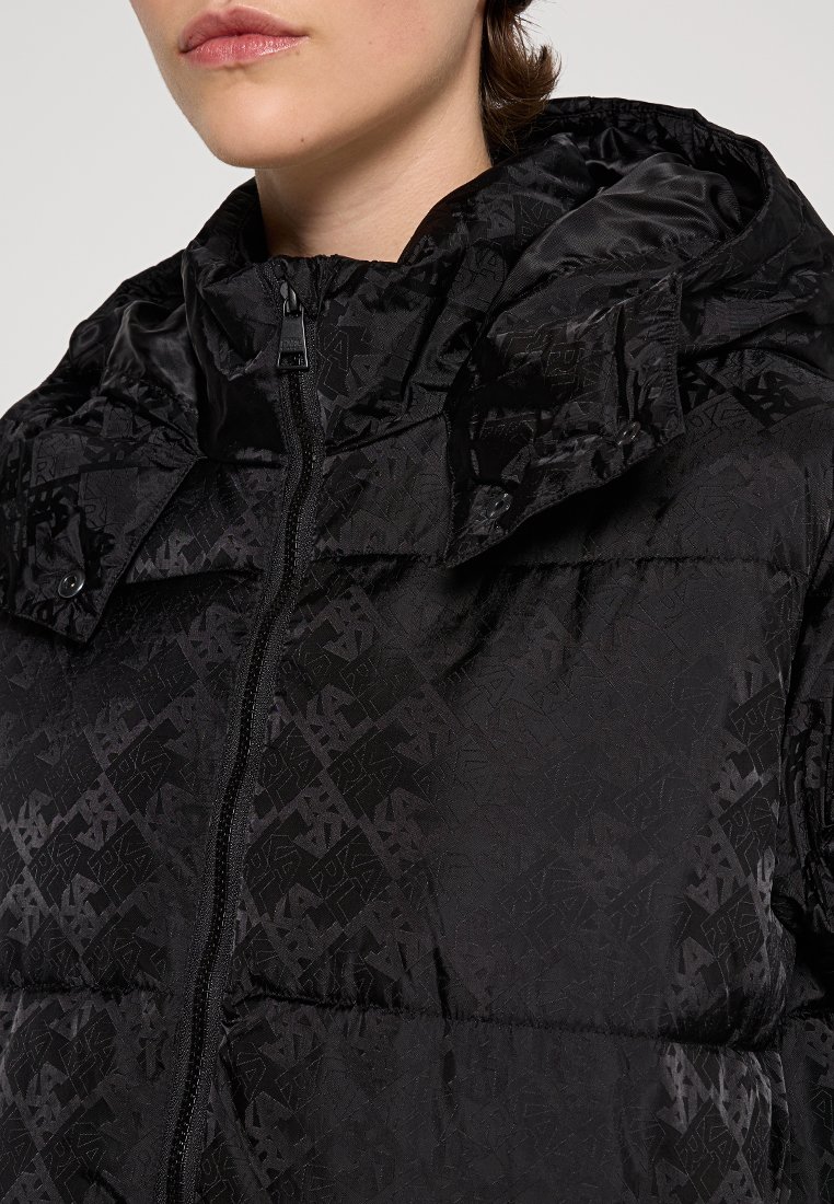 Schwarze Daunenjacke mit strukturiertem geometrischem Muster, Reißverschluss und Kapuze. Das Material wirkt glatt mit einem leichten Glanz.