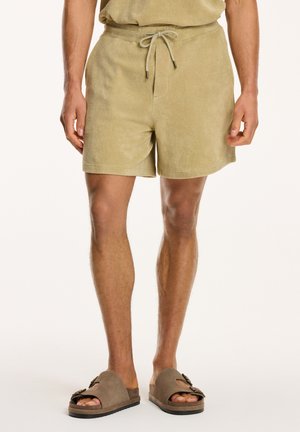 Cotton terry cloth shorts in light olive green, featuring an elastic waistband with drawstring and side pockets.