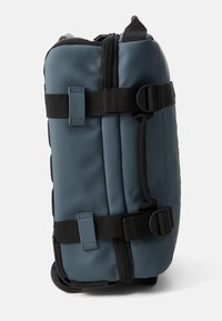 Sac à dos à roulettes en tissu bleu foncé avec des bretelles et des boucles noires. Il dispose d'une fermeture éclair et d'accents texturés. Design compact et structuré.