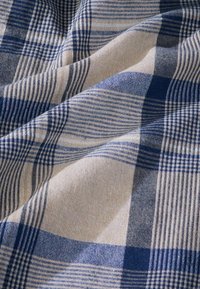 Cotton fabric with a plaid pattern in cream and various shades of blue, featuring woven textures and evenly spaced lines.