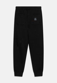 Pantalones deportivos negros con cintura elástica, dos bolsillos traseros, puños acanalados y un pequeño parche de logo en el bolsillo superior derecho.