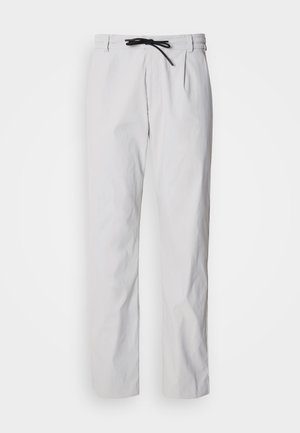 Pantaloni conici din amestec de bumbac, de culoare gri deschis, cu talie reglabilă prin șnur. Prezintă pliuri frontale și buzunare laterale pentru utilitate.