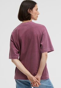 Oversized short-sleeve t-shirt in muted purple cotton with stitched lettering on the back reading "Summer the Label." Casual fit.