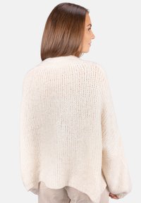 Langärmliger, cremefarbener Strickpullover mit lockerem, cropped Schnitt. Verfügt über ein strukturiertes Muster und weite Ärmel, aus weichem, warmem Material gefertigt.