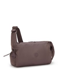 Sac en nylon marron avec bandoulière réglable, fermeture éclair et logo rond. Comprend un pendentif détachable avec un design de visage.