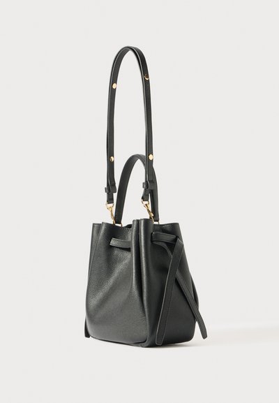 Črna teksturirana usnjena torba v obliki vedra z nastavljivim naramnim trakom, majhnim ročajem in stransko zavezovanje na belem ozadju.