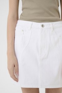 Hvit denimskjørt med en tettsittende design, to frontlommer og knappelukking. Har sømdetaljer og jevn tekstur.