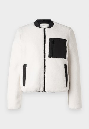 Witte sherpa fleece jas met zwarte ribgebreide kraag, zwarte ritssluiting aan de voorkant, zwarte ritsborstzak en twee handzakken met zwarte bies.