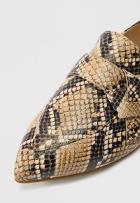 Chaussure à bout pointu en similicuir texturé effet peau de serpent beige et noir, avec un détail de bride croisée à l'avant.