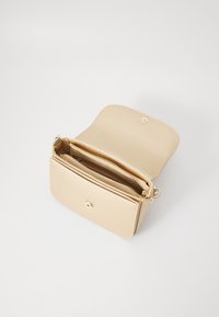 Beige läderhandväska med en strukturerad form, utrustad med knäppstängning, zip-fack och en texturerad yta. Insidan är klädd i matchande tyg.