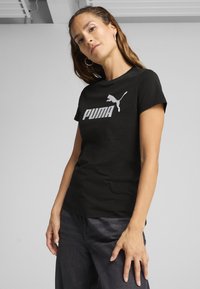 Melns kokvilnas t-krekls ar lielu balto "PUMA" logotipu un lecoša pumā grafiku. Īsas piedurknes ar pieguļošu dizainu.