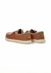Zapatos de tela trenzada marrones con suelas beige, que cuentan con un forro de patrón camo y una etiqueta de logo naranja en la parte trasera. Diseño casual con cordones.
