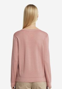 Jasnoróżowy sweter z długim rękawem i okrągłym dekoltem, o gładkiej teksturze i prążkowanym wykończeniu, widziany z tyłu.