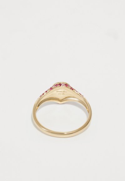 Anello d'oro con una fascia curva che presenta piccole gemme rosse e trasparenti incastonate lungo il bordo superiore, esposto su uno sfondo bianco.