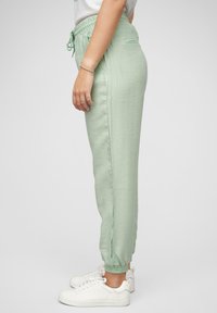 Pantalons de jogging vert clair, fuselés, avec une taille élastique et des poignets, dotés de poches latérales et d'un tissu doux et texturé.