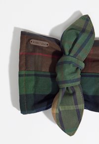 Dodatek z tkaniny w kratę w kolorach ciemnej zieleni, brązu i granatu, z ozdobnym wiązaniem w kokardę oraz metalową metką z nazwą marki "BIMBA Y LOLA".