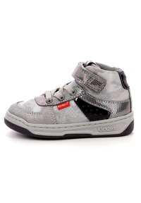 Zapatilla gris de caña alta que presenta una mezcla de materiales texturizados, acentos metálicos, cierre con cordones y Velcro, y un panel lateral negro.