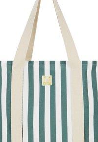 Groene en witte gestreepte draagtas met beige stoffen handvatten; heeft een gele logotag met een afbeelding van de zon en golven. Duurzaam canvasmateriaal.