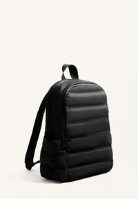 Fekete párnázott hátizsák téglalap alakú, sima textúrával, kétoldali cipzárokkal és felső fogantyúval.
