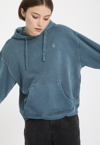 Blauwe katoenen hoodie met een voorzak, trekkoordkap en een klein logo op de borst. Heeft een ontspannen pasvorm en een zachte textuur.
