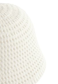 Bob blanc tricoté avec un motif en maille ajourée texturée et un large bord incliné vers le bas.