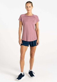 Camiseta atlética de manga corta color rosa claro, pantalones cortos azules y zapatillas negras. La camiseta tiene un escote redondo y un logo en el pecho.