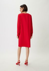 Rotes, langärmliges Kleid mit geradem Schnitt, glatter Textur und Knopfakzenten an den Manschetten. Hat ein dezentes Schlüsselaugen-Detail an der Rückseite.