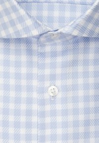 Camicia a quadri azzurro chiaro e bianco con colletto button-down, caratterizzata da un singolo bottone bianco al collo e un design in tessuto testurizzato.