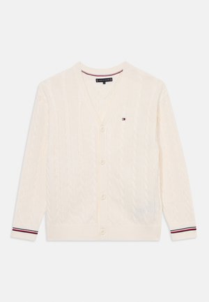 Kremfarget cardigan med kabelstrikkdesign, v-hals, fem knapper og ribbestrikkede mansjetter med røde, hvite og blå striper.
